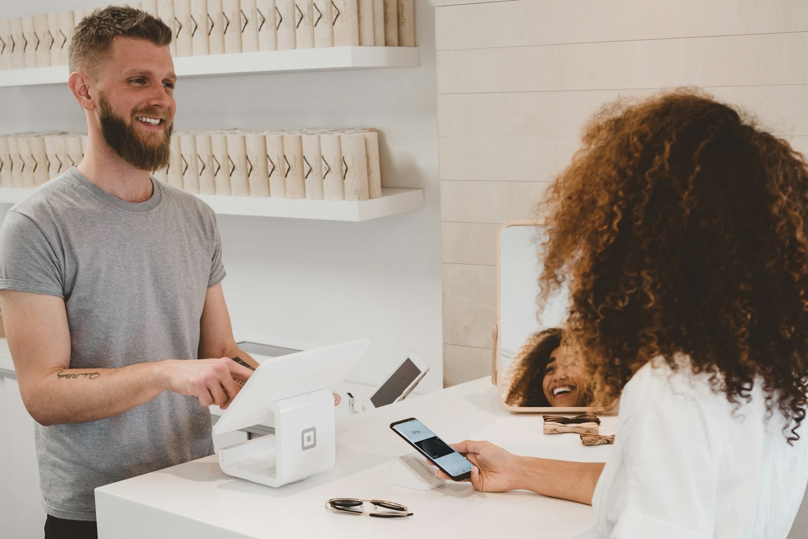 A client paying a small business by card at the counter, the moment HoneyBook pricing fees apply
